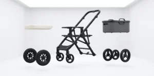 Modular stroller components including black frame, wheels, a storage container, and a cushion displayed in a minimalistic white setting.